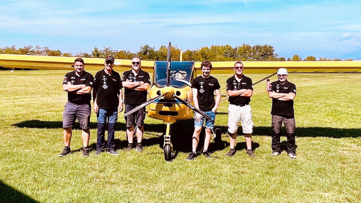 Il team della scuola davanti al Tecnam P92 giallo sul prato del campo volo